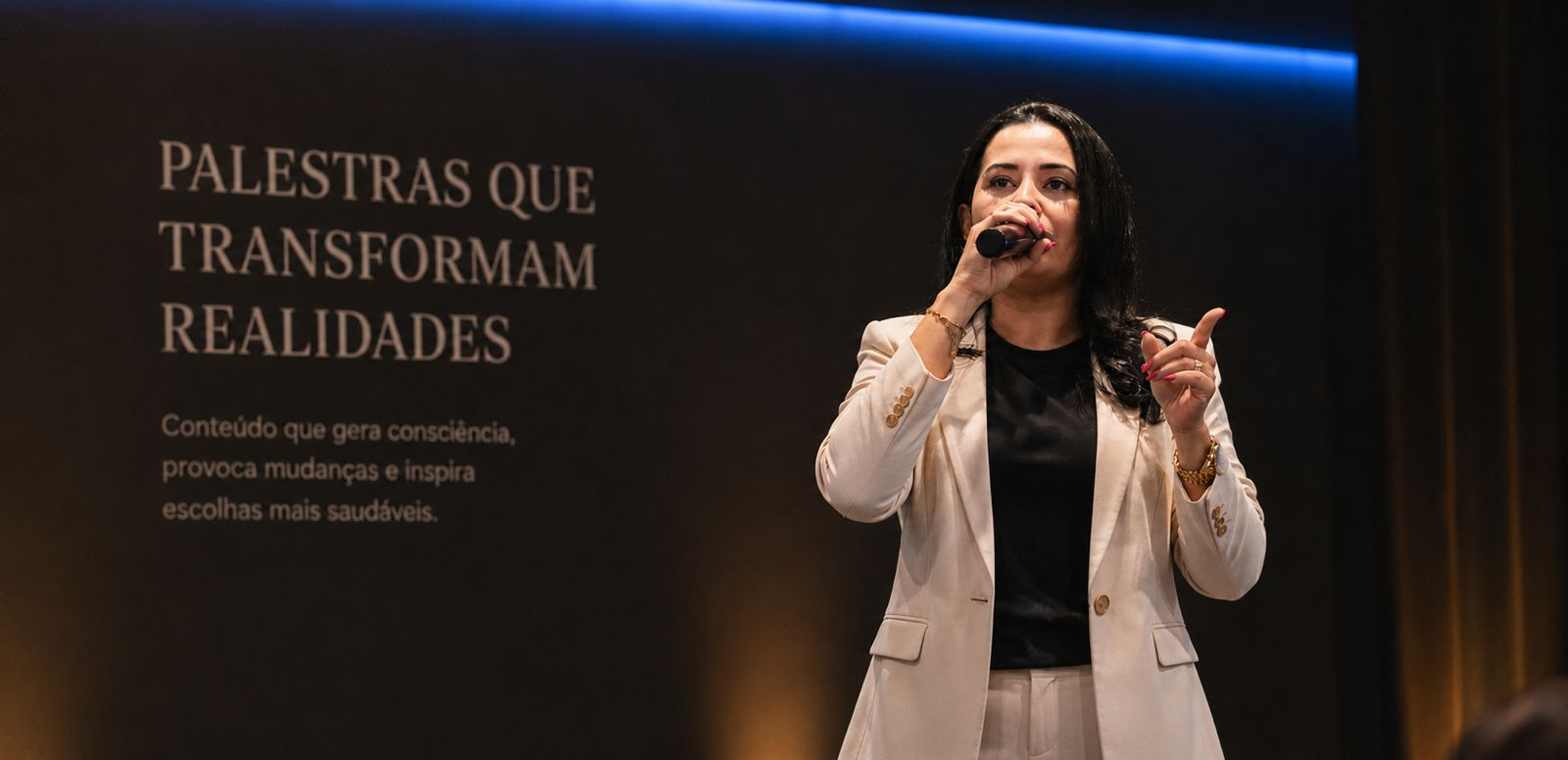 Beatriz da Silva palestrando em palco com fundo escuro